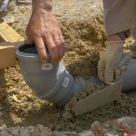 Pouring concrete over plastic pipes.